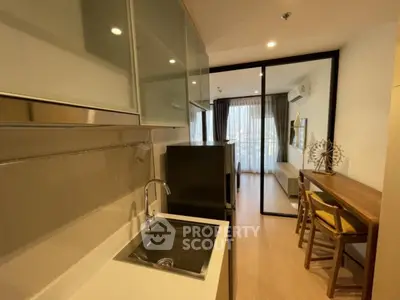 Modern kitchen with sleek design and open layout leading to a cozy living area.