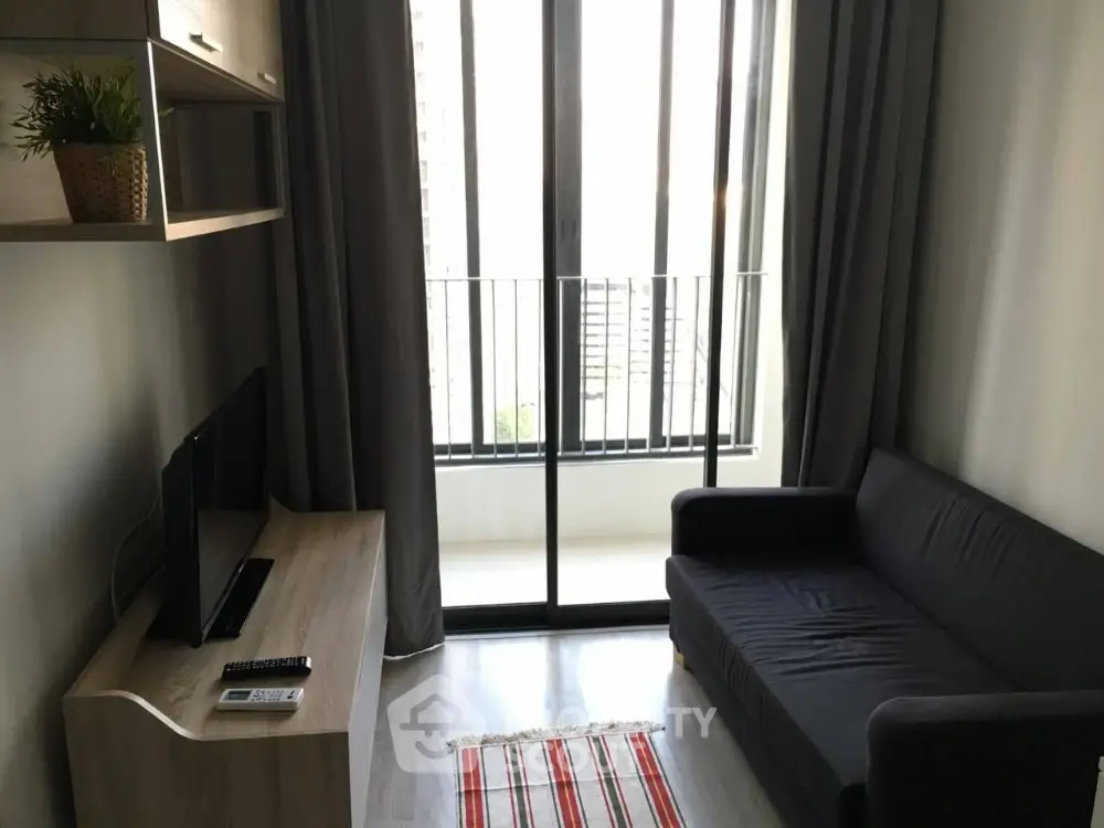 Cozy living room with modern sofa and TV, featuring a balcony view.