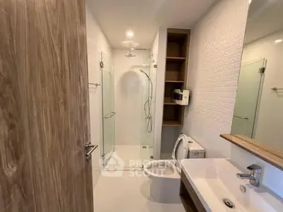 Modern bathroom with glass shower and sleek fixtures in contemporary apartment.