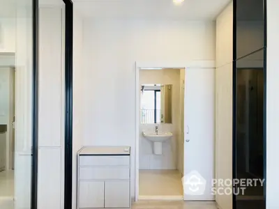 Sleek modern bathroom visible through an open door from a bright, airy bedroom with mirrored wardrobe doors and minimalist decor.