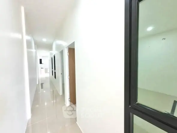 Bright and modern corridor with sleek tile flooring and white walls in a contemporary building.