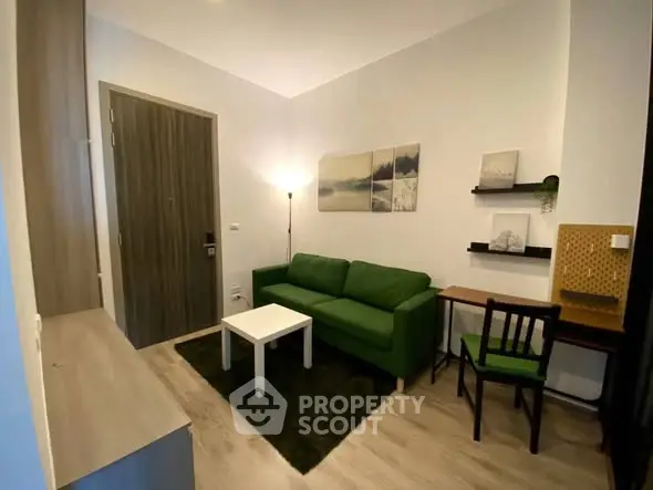 Cozy living room with green sofa, modern decor, and wooden flooring in a stylish apartment.