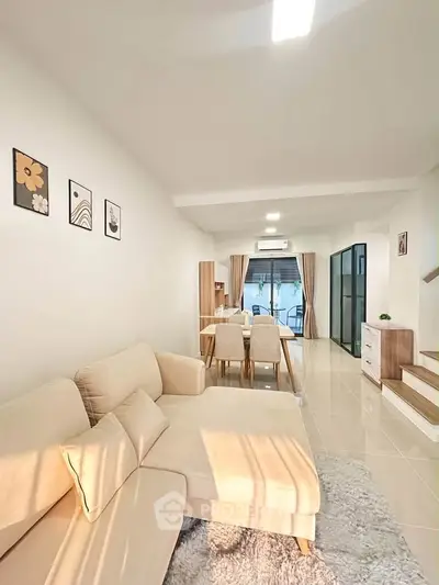 Spacious modern living room with cozy beige sofa and elegant dining area, perfect for family gatherings.