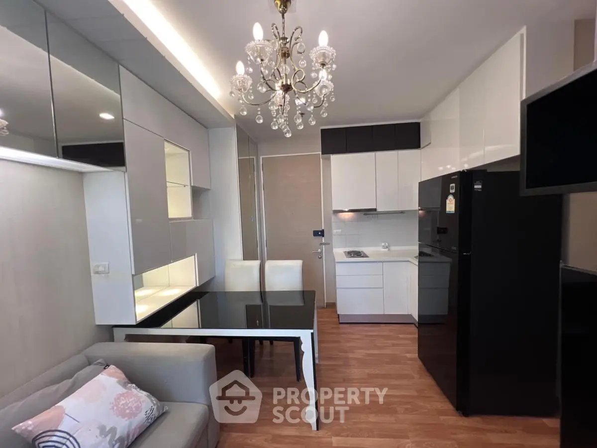 Modern open-layout kitchen and living area with elegant chandelier and sleek furnishings.