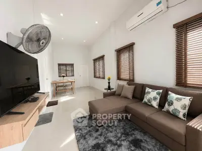 Spacious living room with modern decor, featuring a cozy sectional sofa and large flat-screen TV.