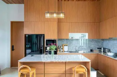Modern kitchen with wooden cabinetry, marble island, and stylish lighting