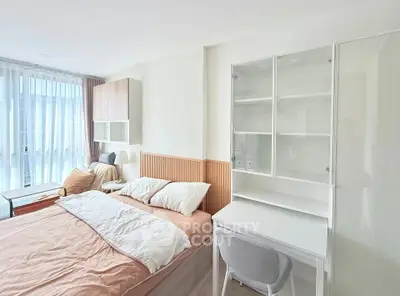 Modern bedroom with stylish decor and natural light, featuring a cozy bed and functional workspace.