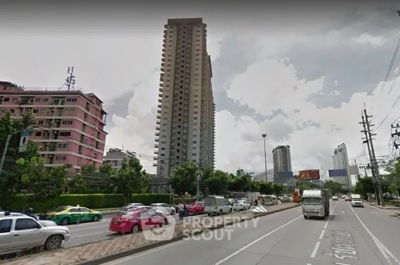High-rise residential building with urban street view and traffic in bustling city area.