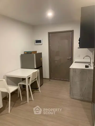 Modern compact kitchen with sleek design and dining area in a cozy apartment.