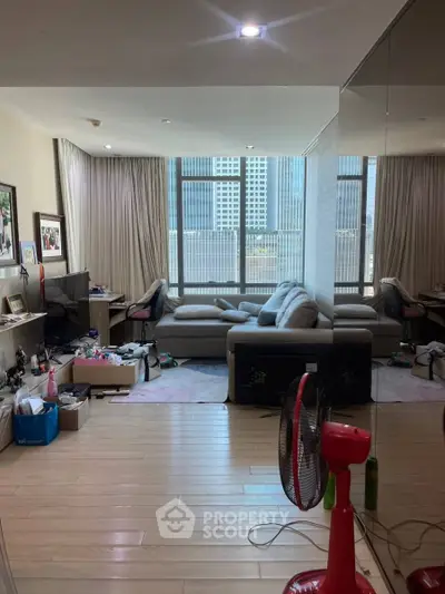 Spacious living room with large windows and modern furniture in urban apartment.