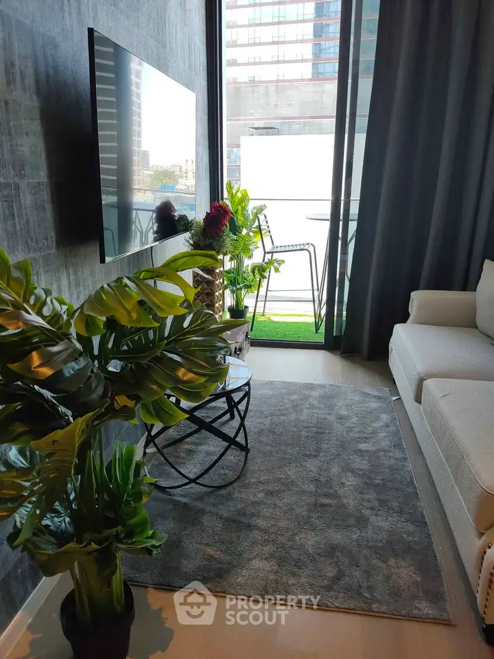 Modern living room with large TV and balcony view, featuring stylish decor and natural light.