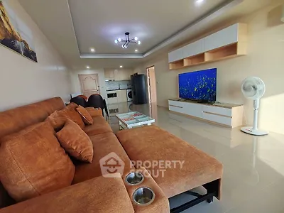 Spacious living room with modern decor and large TV, perfect for relaxation and entertainment.