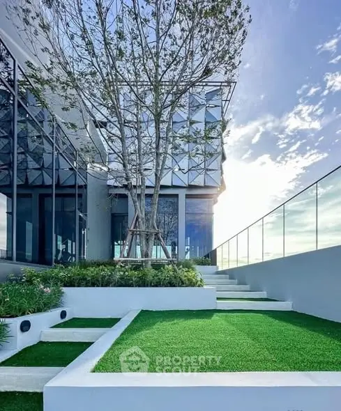 Modern architectural building with lush green rooftop garden and glass railing.