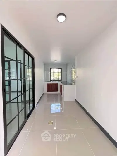 Modern kitchen with sleek design and sliding glass doors, featuring glossy tiled flooring and ample natural light.