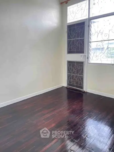 Spacious room with wooden flooring and large windows, perfect for natural light.