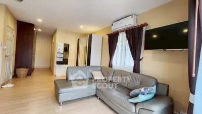 Modern living room with sleek gray sofa and wall-mounted TV, featuring warm lighting and stylish decor.