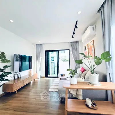 Modern living room with stylish decor, large TV, and natural light from sliding glass doors.