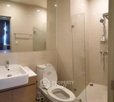 Modern bathroom with glass shower and sleek fixtures in contemporary apartment.