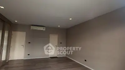 Spacious empty room with wooden flooring and air conditioning, ready for customization.