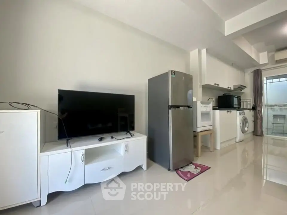 Modern apartment interior with sleek kitchen and living area featuring TV and appliances.