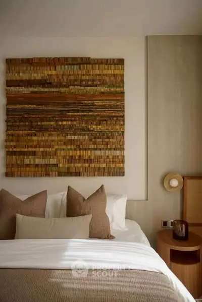 Cozy bedroom with stylish decor and warm lighting, featuring a textured wall art above the bed.