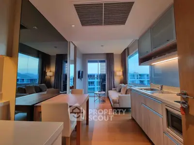 Modern open-plan living room and kitchen with stylish decor and large windows offering natural light.