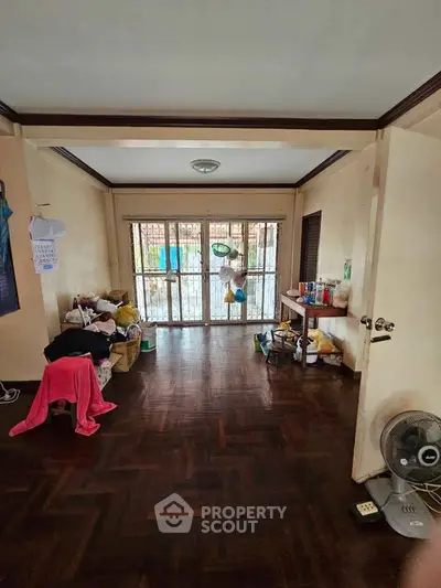 Spacious living room with wooden flooring and large windows for natural light.