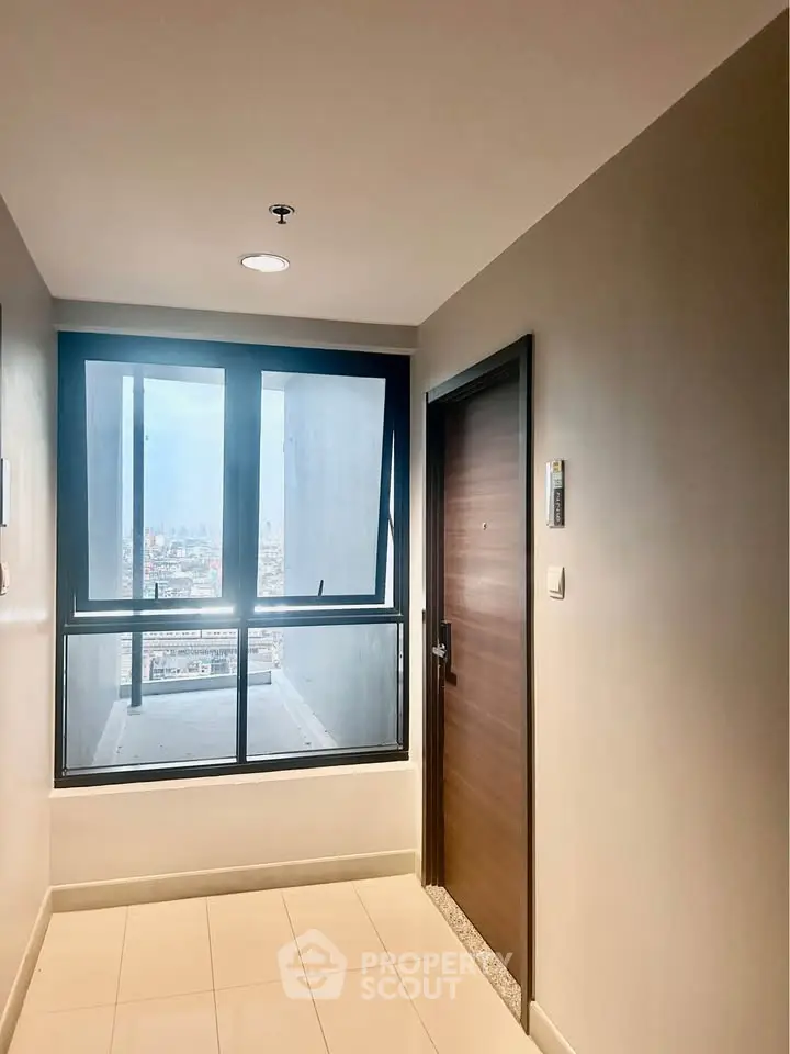 Modern apartment entrance with city view through large window, showcasing sleek design and natural light.