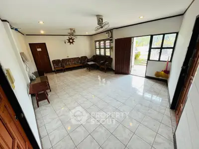 Spacious living room with tiled floor and ample natural light, perfect for family gatherings.