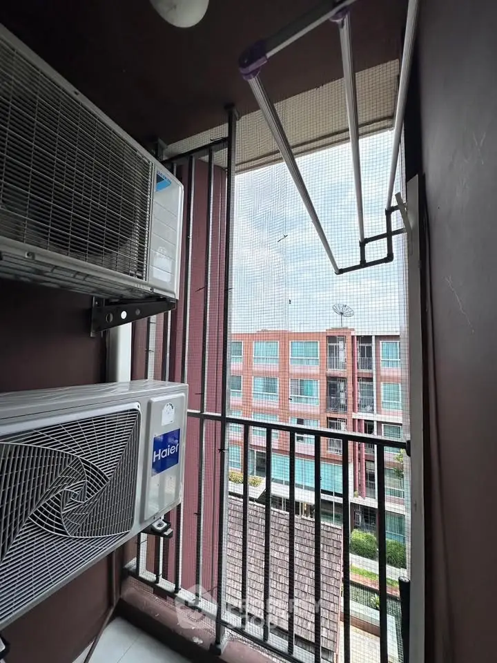 Compact balcony with air conditioning units and a view of neighboring buildings.