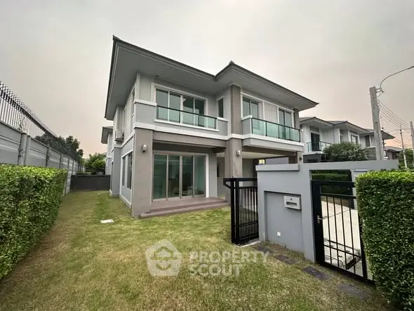 Modern two-story house with manicured lawn and secure gate in suburban setting.