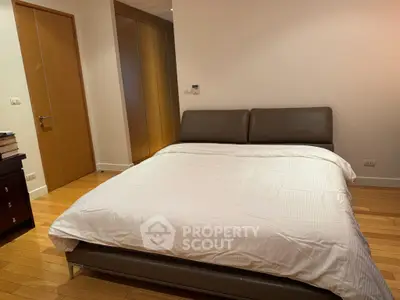 Spacious bedroom with modern bed and wooden flooring in a stylish apartment.