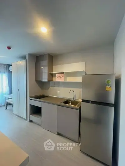Modern kitchen with sleek cabinets and stainless steel fridge in a cozy apartment.