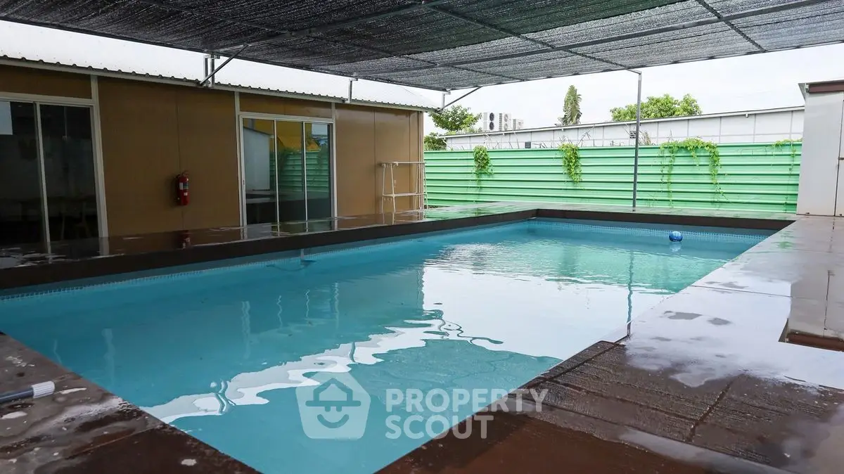 Spacious outdoor pool with modern design and shaded area, perfect for relaxation and entertainment.