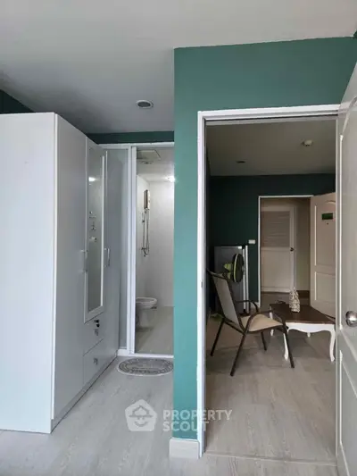 Modern apartment interior with green walls, featuring a compact bathroom and cozy seating area.
