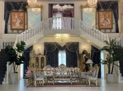 Luxurious living room with elegant decor, grand staircase, and opulent chandeliers in a lavish estate.