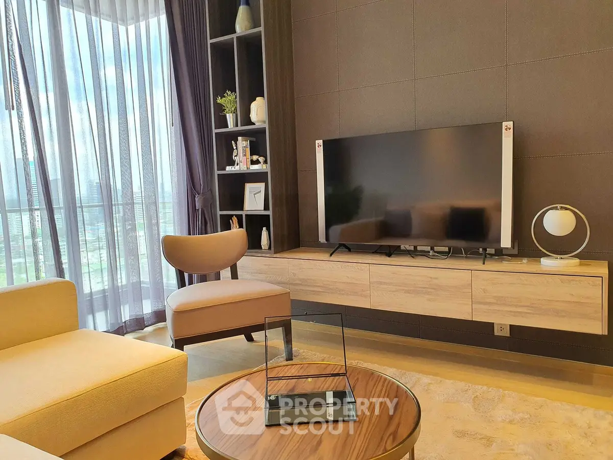 Modern living room with stylish furniture and large TV, featuring floor-to-ceiling windows with city view.