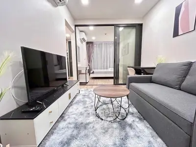 Modern living room with sleek furniture and open layout, featuring a cozy sofa and large TV.