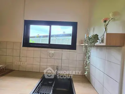 Modern kitchen with sleek sink and window view, featuring elegant tile backsplash and minimalist decor.