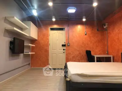 Modern bedroom with orange accent wall, sleek shelving, and minimalist decor.