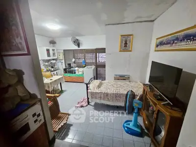 Cozy living room with TV, fan, and kitchen area in a compact home setting.