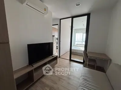 Modern apartment interior with living room and bedroom, featuring sleek furniture and natural light.