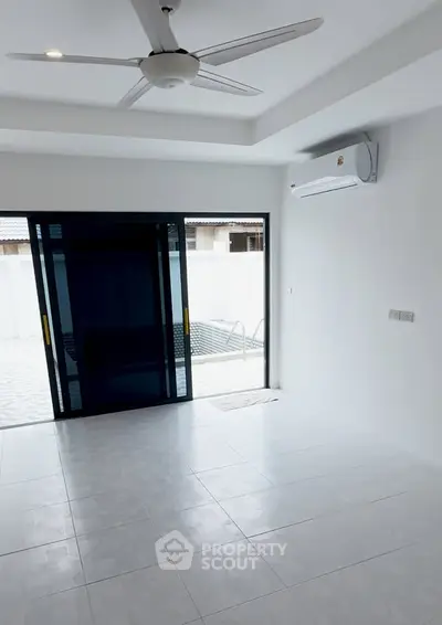 Spacious modern living room with ceiling fan and air conditioning, featuring large sliding glass doors.