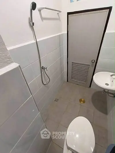 Compact bathroom with shower, toilet, and sink in a minimalist design.