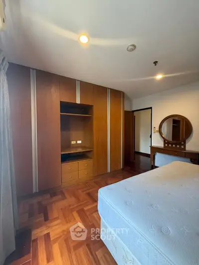 Spacious bedroom with wooden flooring and built-in wardrobe, perfect for modern living.