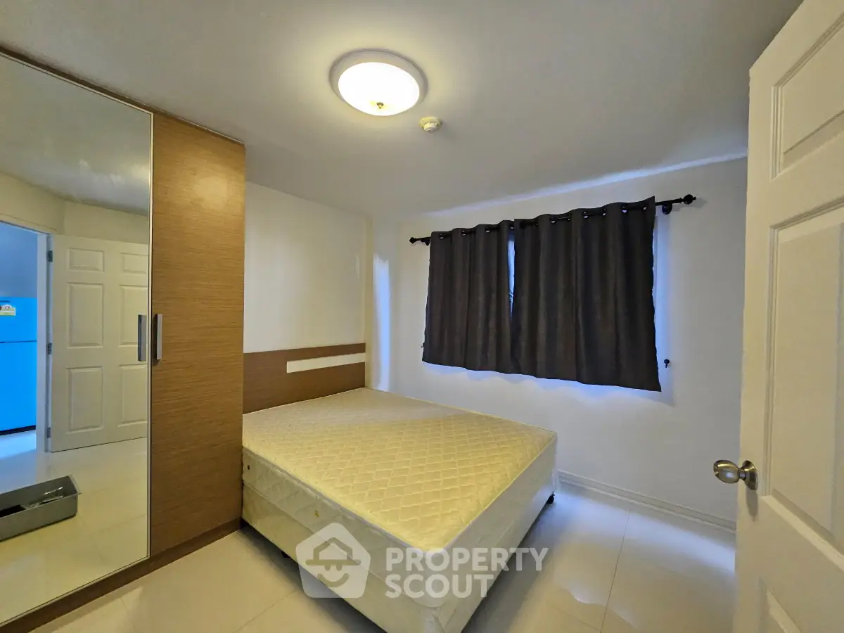 Spacious bedroom with large wardrobe and natural light, perfect for comfortable living.