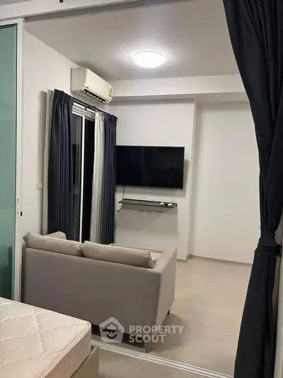 Modern living room with sleek TV setup and cozy sofa, featuring elegant curtains and minimalist design.