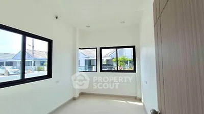 Bright room with large windows offering a view of modern houses, ideal for a cozy study or office space.