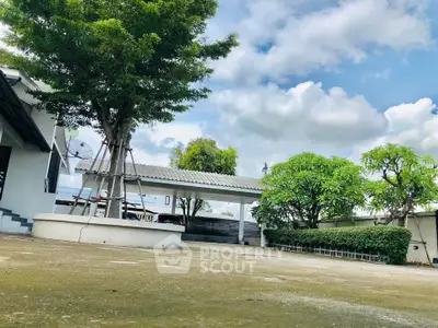 Spacious outdoor area with lush greenery and clear blue sky, perfect for relaxation and outdoor activities.