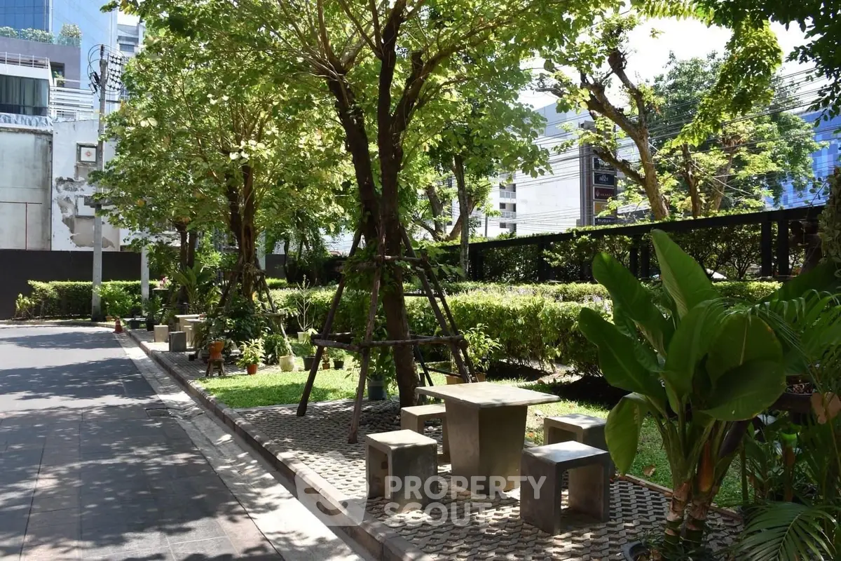 Charming urban garden with seating area, lush greenery, and modern city backdrop.